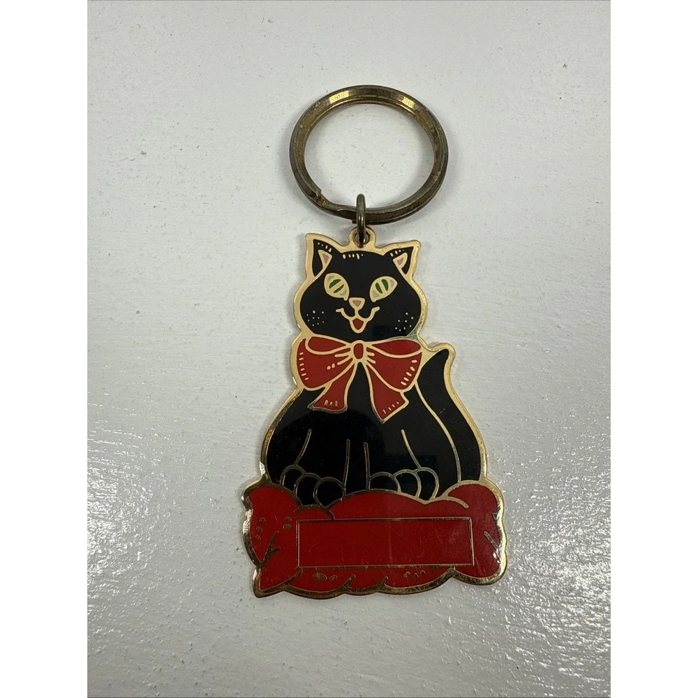 Black cat enamel keychain with gold-toned metal accents and‎ a red bow